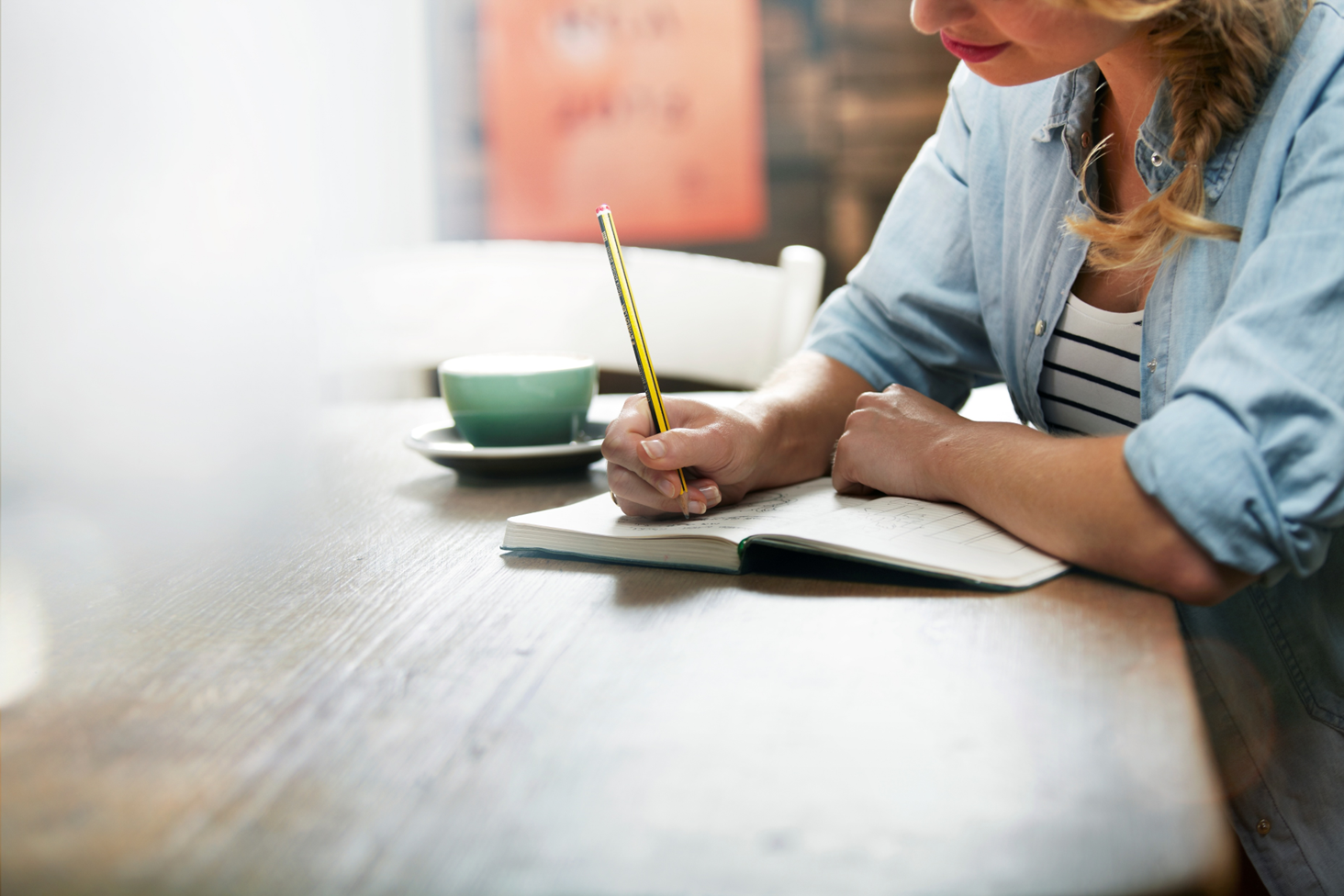 A student having a hot drink and writing in a notebook